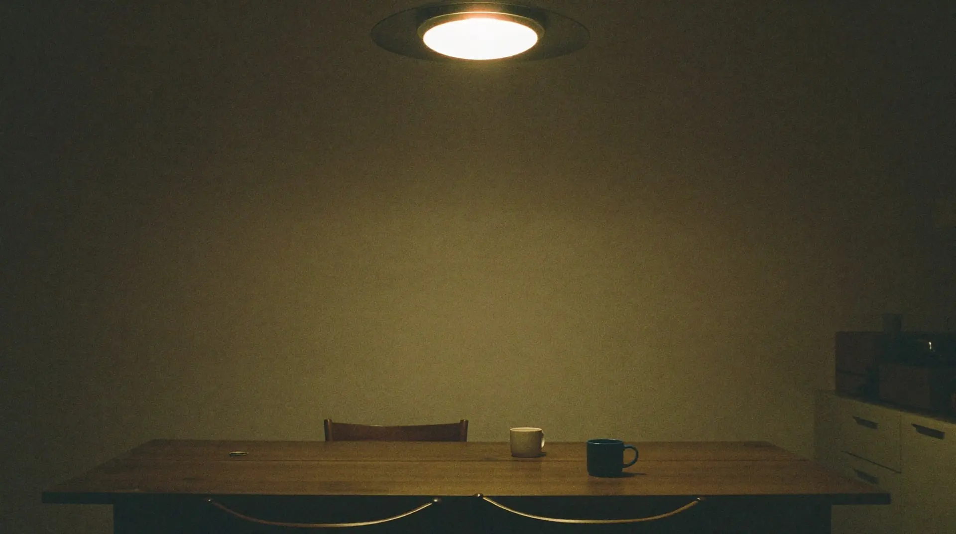 Cozinha de casa acesa de madrugada, com duas xícaras sobre a mesa. Imagem editorial; não é uma foto do complexo.